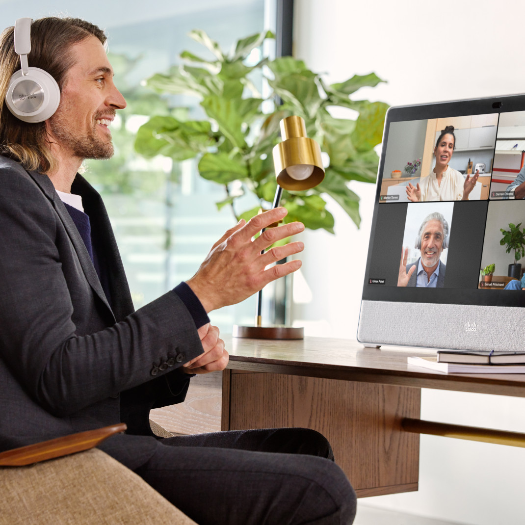 Smiling person in a headset video conferences with colleagues from his office.