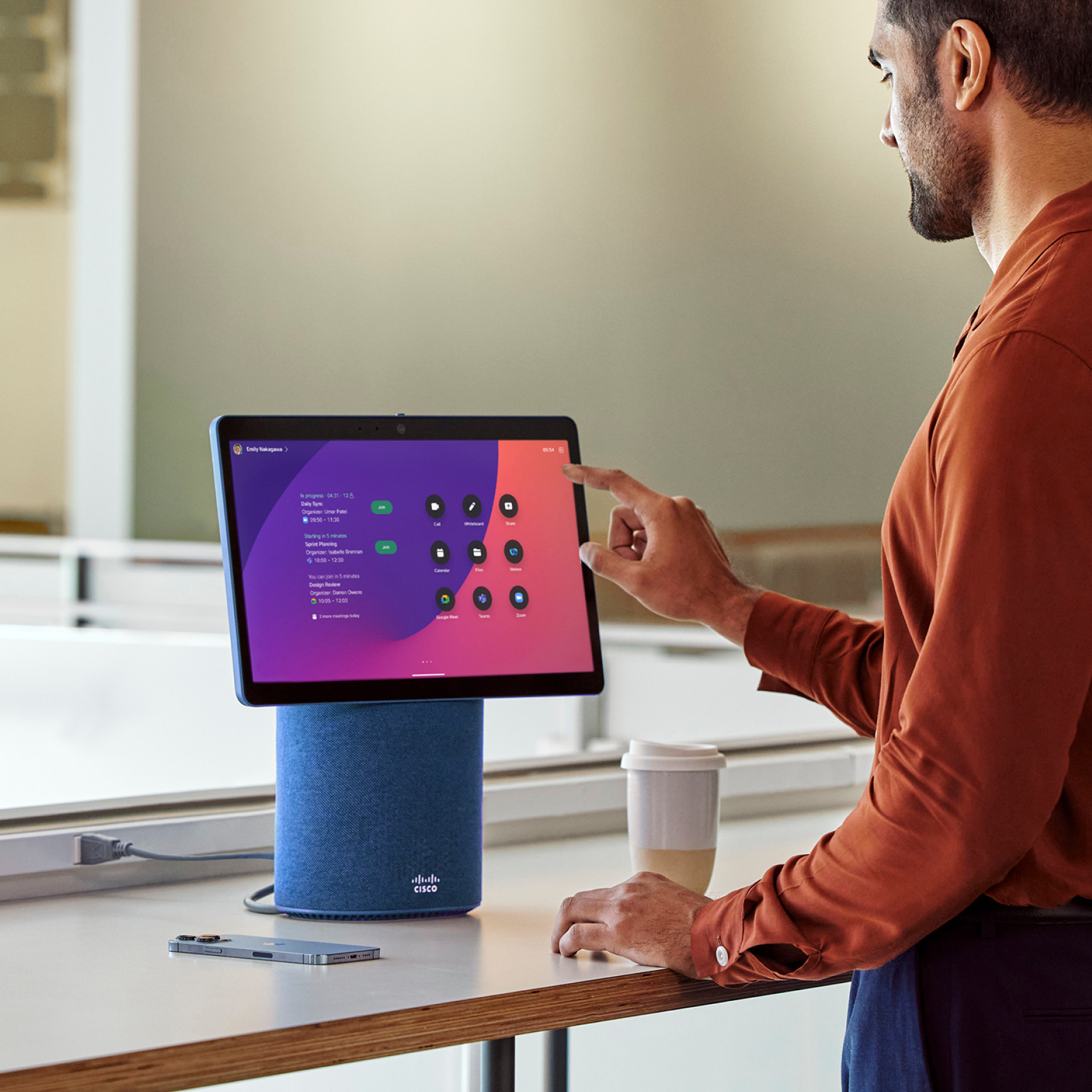 Person taps Webex Desk Mini’s touch screen to join Zoom meeting. Screen shows apps like Google Meet, Microsoft Teams, and Zoom